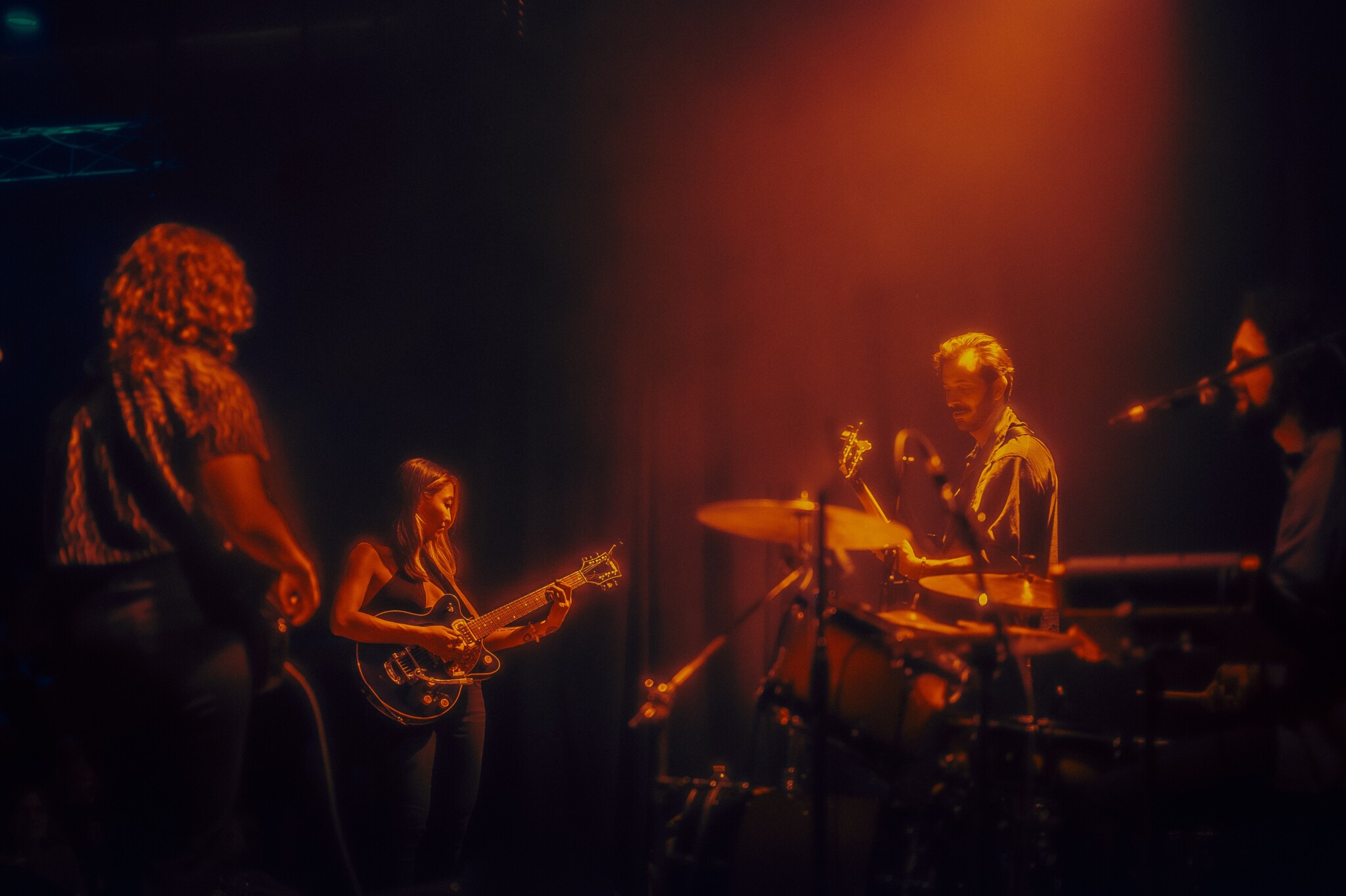 A folk rock band performs on stage under orange lighting.