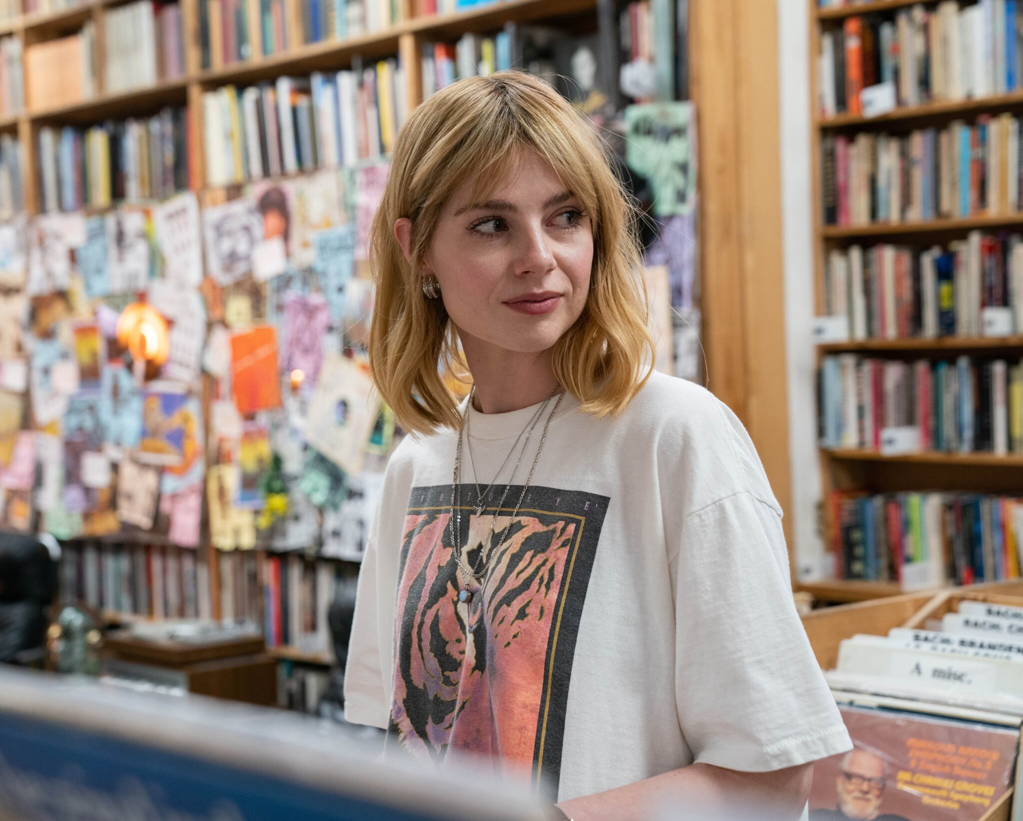 Lucy Boynton in "The Greatest Hits" stands in a record shop.